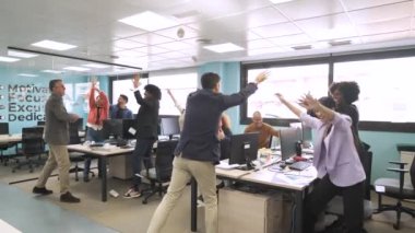 Erkek yönetmenin, başarılı bir işten sonra modern ofiste bilgisayarlarla ayakta duran mutlu meslektaşlarına para atması yavaş bir hareket.