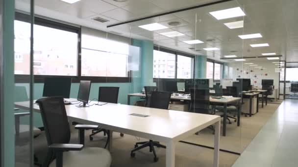 天井とガラスの窓が付いている椅子の近くのテーブルのコンピュータが付いている現代広々としたオフィスのインテリアデザイン — ストック動画