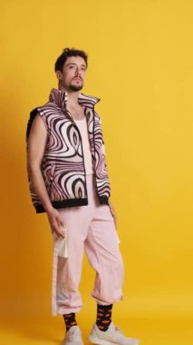 Fotoğraf stüdyosunda pembe modern kıyafetlerle poz veren eşcinsel bir adama yaklaşan kameralı bir video.