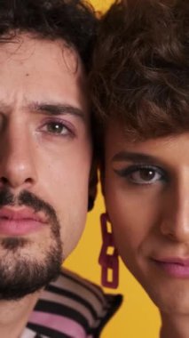 Makyajlı ciddi bir eşcinsel çiftin sarı arka plandaki kameraya baktığı videoyu kapat.