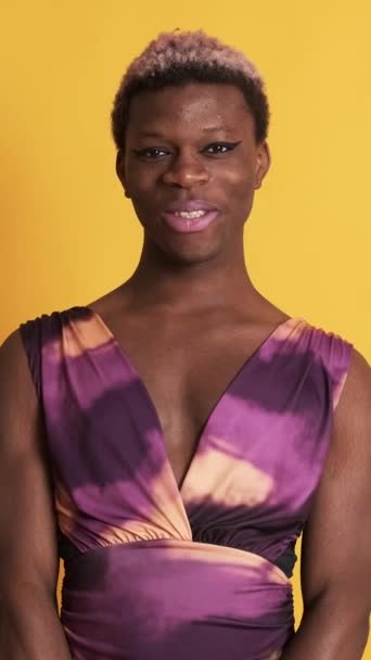 カラフルなドレスを持つ黒いトランスジェンダーの人物のビデオとカメラで笑顔を作る — ストック動画