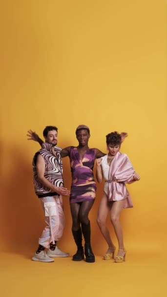 三个快乐的多种族变性男子在一个黄色背景的摄影演播室里跳舞 玩乐的视频 — 图库视频影像