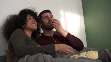 Haftasonu evlerinde film seyrederken kanepede rahat rahat oturup mısır fırlatan genç bir çift.