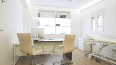 Gündüz vakti bilgisayar masasında sıralanmış sandalyeleri olan geniş, modern, parlak bir kliniğin içinde.