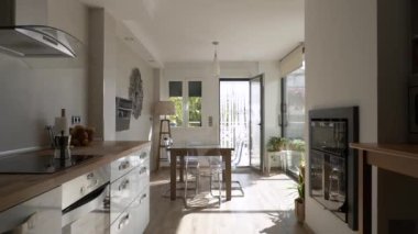 Camdan duvarları olan parlak bir evin mutfağının içinde seyahat eden bir video.