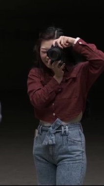 Genç Asyalı kadın fotoğrafçı profesyonel bir kamerayla birine fotoğraf çekiyor.