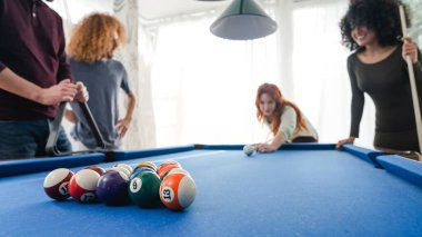 Hafta sonu partisinde arkadaşlarıyla bilardo oynarken bilardo oynayan genç bir kadın.