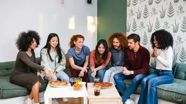 stock image Group of multiethnic male and female friends discussing over delicious pizzas and drinks in living room during weekend party at home