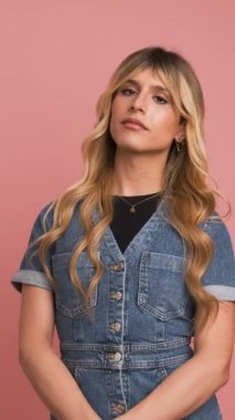 Pembe arka planda kameraya bakarken kot elbiseli kendinden emin transseksüel kadın pozu