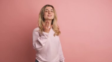 Yavaş çekimde, pembe arka planda, öpüşen ve gülümseyen güzel bir kadının videosu.