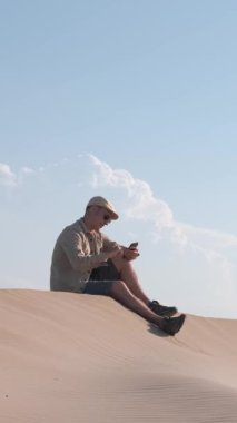 Sadece çöl tepelerinde internet bağlantısı olan akıllı telefon kullanan bir adam.