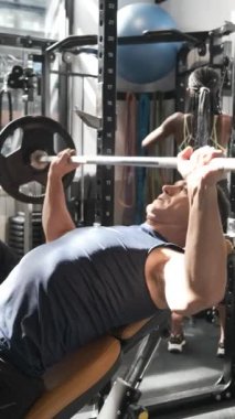 Spor salonunda ağırlık kaldıran bir adamın yavaş çekim videosu.