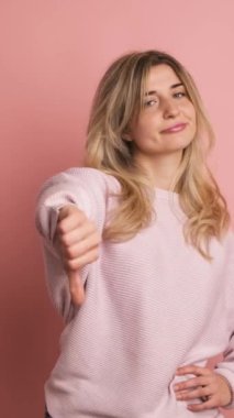 Yavaş çekimde, pembe arka planda, kendine güvenen bir sarışının parmak ucunda anlaşmazlık gösteren bir stüdyo videosu.