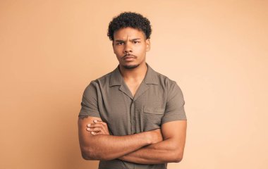 Aynı fikirde olmayan Brezilyalı genç bir erkeğin portresi. Günlük giysiler içinde. Bej arka planda kameraya bakarken başlarını çapraz şekilde sallıyor.