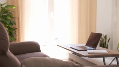 Dolly 'nin dizüstü bilgisayarı ve günlüğü evdeki rahat oturma odasındaki rahat koltuğun yanındaki ahşap masada.