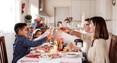 Mutlu aile Noel yemeğinde şarap ve suyla kadeh kaldırıyor.