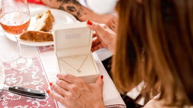 Tanınmayan bir kadın Noel hediyesi olarak aldığı kolyeye bakıyor.