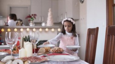 Evde Noel masasını hazırlayan beyazlı bir kızın yavaş çekim videosu.