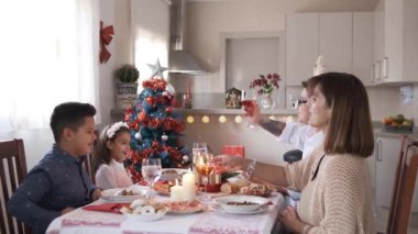 Noel yemeğinde şarap ve suyla kadeh kaldıran mutlu bir ailenin yavaş çekim videosu.