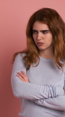 Stüdyo videosu, genç bir kadının kollarını kavuştururken kafasıyla hareketler yaptığı pembe bir arka plan. Dikey Görüntü