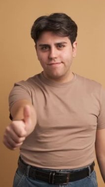 Stüdyoda, kahverengi geçmişli, el kol hareketi yapan genç adam.