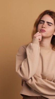 Yüz hatları ve düşünceli ifadesiyle genç bir kadının kahverengi geçmişine sahip bir stüdyo videosu. Dikey Görüntü