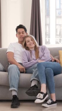 Oturma odalarındaki koltukta oturan genç çift rahat ve rahat bir atmosferde fotoğraf çektirmek için mutlu poz veriyorlar.