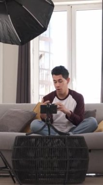 Kanepede oturan fotoğrafçı kamera özelliklerini tartışıyor ve meşgul bir seyirciyle görüşlerini paylaşıyor.