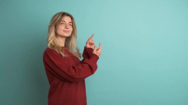 Kestane rengi arabalı mutlu genç kadın, çalışma alanının mavi arkaplan üzerine yazılan metin için boş yer modelini gösteriyor.