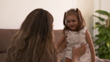 Şakacı, genç Latin anne ve kızının evdeki rahat oturma odasındaki kanepede surat asıp büzüşmesi.