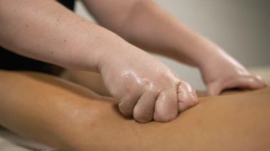 Masör müşterinin bacaklarını ovuyor, rahatlatıcı ve iyileştirici bir masaj sağlıyor.