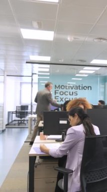 Olgun erkek yönetici, yaratıcı çalışma alanındaki profesyonellere iş verdiği için dosyaları mutlu çoklu etnik çalışanlara veriyor.