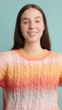 Genç bir kadın, küçük bir hediye kutusunu kırmızı kurdeleyle sunar. Mavi arka planda heyecan ve mutluluğu ifade eder.