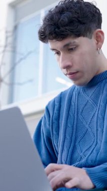 Dizüstü bilgisayarı üzerinde çalışan, modern bir üniversite kampüsünde okuyan ve öğrenen genç bir öğrenci. Dikey görüntüler