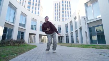 Dinamik kadın dansçı kentsel mimari arka plana karşı serbest stil hareketleri sergiliyor, enerjik çağdaş sokak dansı yoluyla sanatsal tutkularını ifade ediyor