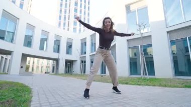 Modern kentsel mimariye karşı zarif bir hareketle sanatsal özgürlüğü ifade ederek çağdaş dans figürleri sergileyen dinamik bayan dansçı.