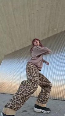 Modern mimari zemin üzerinde akışkan hareketler yapan dinamik şehir dansçısı, yüksek enerji koreografisi ve sokak esinlenilmiş ritmiyle çağdaş dans tarzını ifade ediyor.