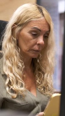 İş kadını telefonundan bir şey okuyor ve çeşitli yüz ifadeleriyle tepki veriyor. Dikey görüntüler