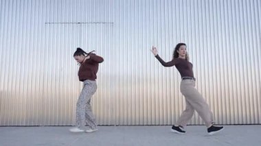 Genç kadınlar dinamik dans hareketlerini titizlikle ve enerjiyle gerçekleştiriyor, endüstriyel metallere karşı çağdaş koreografi sergiliyorlar.