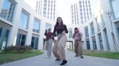 Modern bir binanın avlusunda modern bir koreografi sergileyen bir grup kadın dansçı.