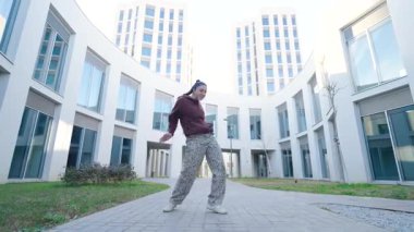 Şehir ortamında dinamik hareketler sergileyen yetenekli sokak dansçısı dans yoluyla enerji ve tutku ifade ediyor.