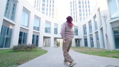 Gösterişli mimari arkaplana karşı dinamik hareketler sergileyen kadın dansçı, kentin modern manzarasında kendinden emin ve anlamlı hareketlerle şehir dans tarzını sergiliyor.