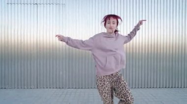 Canlı kadın dansçı endüstriyel metal duvara karşı hareketler sergiliyor, enerjik modern sokak dansı stili ile tutkuyu ifade ediyor.