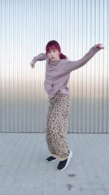 Şehir dansçısı metalik arka plana karşı tutkulu enerjisiyle dinamik hip hop hareketleri yapıyor, sokak dansı yaratıcılığını ve bireysel stilini vurguluyor