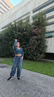 Modern bir binanın önünde çeşitli hareketler sergileyen enerjik dansçı dinamik şehir dansı performansı yaratıyor.