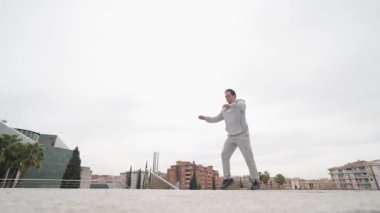 Parkur atleti dinamik bir cephe oluşturarak çeviklik ve hassasiyet göstererek, gündüz eğitim seansı boyunca şehir çatısı üzerinde olağanüstü bir beceri gösteriyor.