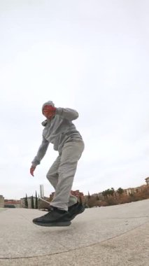 Sokak dansçısı şehir manzarasında güçlü koreografi yoluyla sanatsal becerilerini ifade ederek yüksek enerjiyle dinamik hip hop hareketleri sergiliyor.