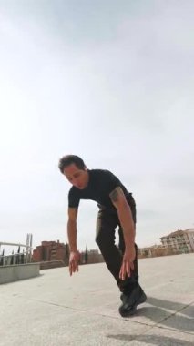 Şehir manzarasında çağdaş hareketler yapan dinamik erkek dansçı, güçlü, akışkan hareket ve atletik beceri yoluyla sanatsal ifadeyi somutlaştırıyor