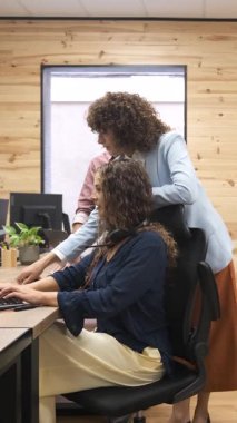 Modern bir ofis ortamında, masasındaki tele pazarlamacıya bir iş görevini açıklayan bir yönetici. Dikey görüntüler