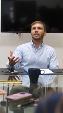 İş adamı iş arkadaşlarıyla yaptığı bir toplantıda el kol hareketi ve konuşma yaparak başarı için fikirlerini ve stratejilerini paylaşıyor. Dikey görüntüler